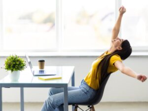 mujer-negocios-relajandose-manos-detras-cabeza-sentada-silla-oficina-675x450